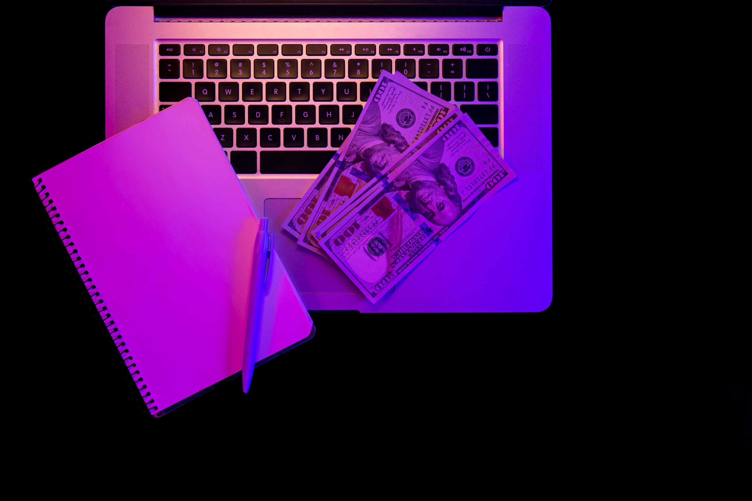 laptop blank notepad paper money neon lighting top view scaled